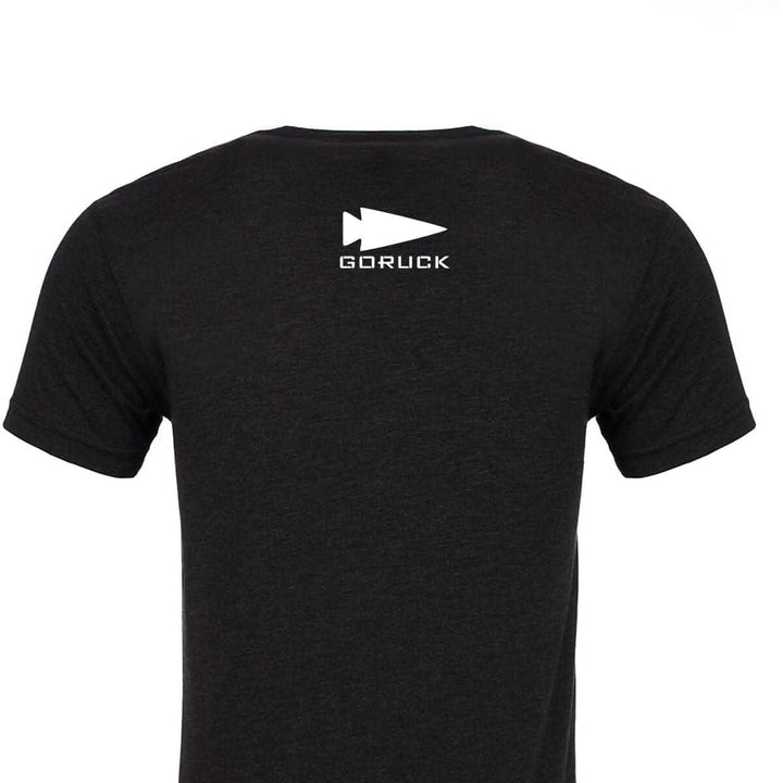 View of the back of a black America Tee - Tri-Blend from vendor-unknown, featuring a white GORUCK logo with an arrowhead design at the top center, printed in the USA.