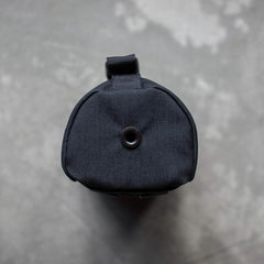 Top view of a compact black GORUCK full panel water bottle pocket with drainage grommet on grey concrete