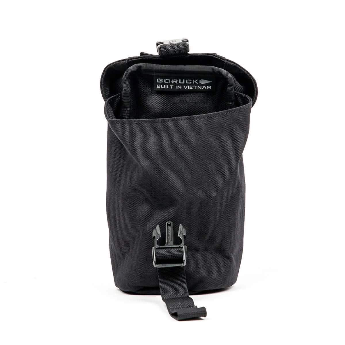 A black, cylindrical GORUCK Full Panel Water Bottle Pocket with a buckle strap. Inside, there's a label stating it's Built in Vietnam. It includes a MOLLE attachment system for customizable carry options and is open to display its spacious interior, ideal for organizing essentials.