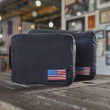 GORUCK black packing cubes with American flag patch on wooden table in rustic room