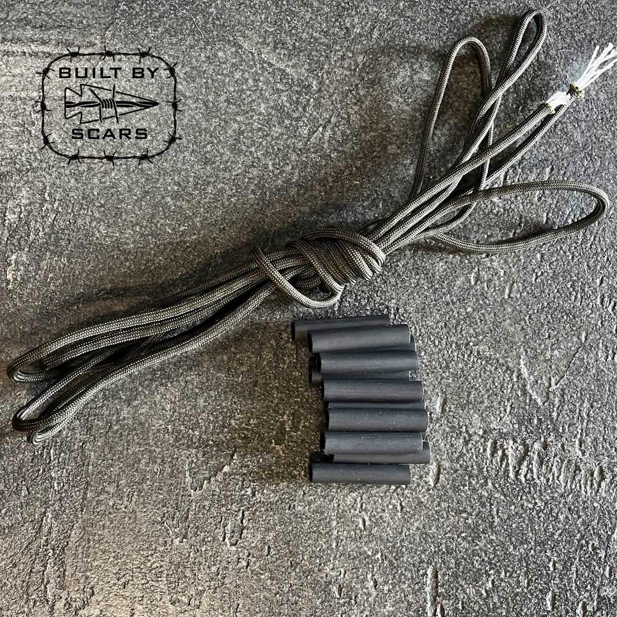 A coiled black rope, accompanied by multiple black tubes that appear to be heat shrink tubes, rests on a textured gray surface. In the top left corner, a logo showcasing a star and arrow displays the text 