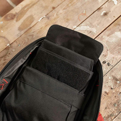 A GORUCK Ruck Sandbag - 10LB in black sits on a wooden surface with its partially open compartments displaying an orderly storage space filled with dark-colored items. The bag is equipped with a secure VELCRO® closure to keep your essentials safe during any adventure.