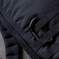 Close-up of black GORUCK rucksack featuring sturdy webbing straps and branded metal carabiner hook