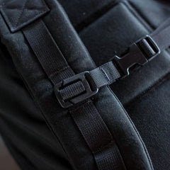 Close-up of a GORUCK backpack, highlighting its durable Training Sternum Strap and fastening system. The focus is on a black buckle secured with an adjustable strap, enhanced by MOLLE webbing for added versatility.