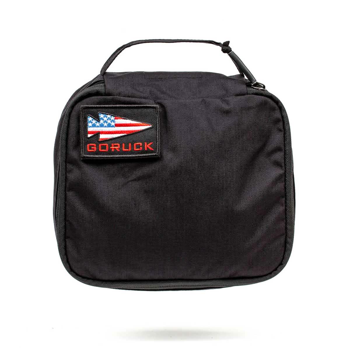 Introducing the Shadow Pockets by GORUCK—a durable black travel pouch made from Cordura. Designed for optimal ruck organization, it includes a convenient handle. The front patch proudly displays an American flag arrowhead and the word "GORUCK," showcasing its compact and functional design.