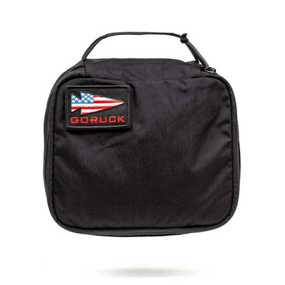 Introducing the Shadow Pockets by GORUCK—a durable black travel pouch made from Cordura. Designed for optimal ruck organization, it includes a convenient handle. The front patch proudly displays an American flag arrowhead and the word "GORUCK," showcasing its compact and functional design.