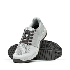 The Ballistic Trainers - Slick - Lunar Rock + Charcoal are versatile light gray athletic sneakers with black laces and textured soles, perfect for functional fitness workouts.