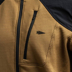 Close-up of the Men’s Full Zip - Polartec Grid Fleece by GORUCK, featuring a brown design with a black zipper and small black arrowhead logo on the chest. Crafted from ToughDry Fabric, this jacket showcases textured fabric and black accents along the shoulders.