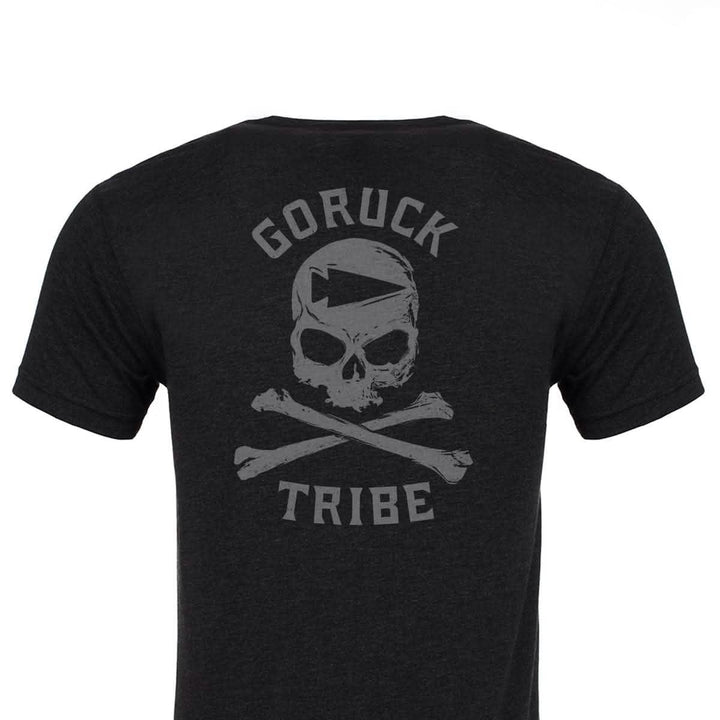 A GORUCK Tribe Tee - Tri-Blend in black showcases a striking design on the back, featuring a skull and crossed bones. "GORUCK Challenge" is prominently displayed above, with "TRIBE" printed below, encapsulating the essence of shared pain and unity inherent in every GORUCK Tribe adventure.