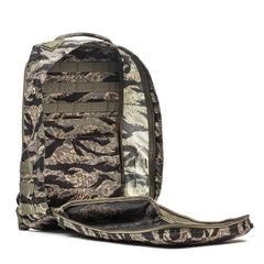 The GR1 - USA - Tiger Stripe backpack, featuring a camouflage pattern, is displayed with its main compartment unzipped and open against a white background.