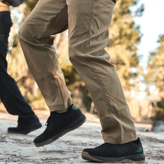 Close-up of person wearing tan GORUCK pants and black rucking shoes walking outdoors on dirt path
