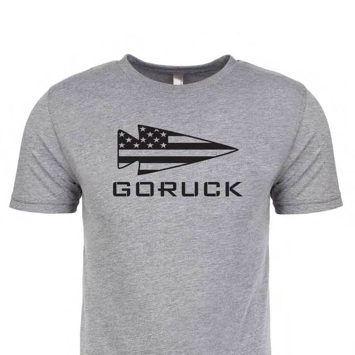 The GORUCK USA Tee - Tri-blend from vendor-unknown is a premium gray T-shirt that showcases "GORUCK" alongside a stylized arrow logo with the American flag, capturing the essence of the GORUCK spearhead.