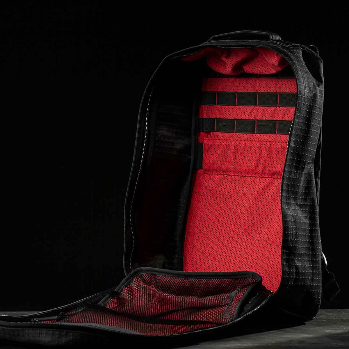 Open GR1 USA x Carryology - GRXC2 Samurai backpack in black with a red interior, showing mesh and textured compartments made from premium Japanese cotton, set against a black background.