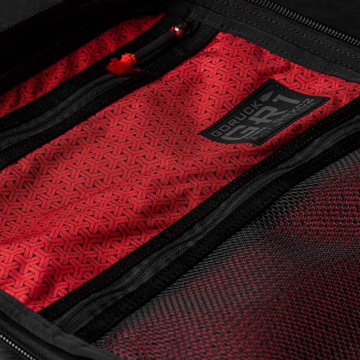 Close-up of an open backpack pocket lined with red patterned Japanese cotton fabric, featuring the GR1 USA x Carryology - GRXC2 Samurai label.
