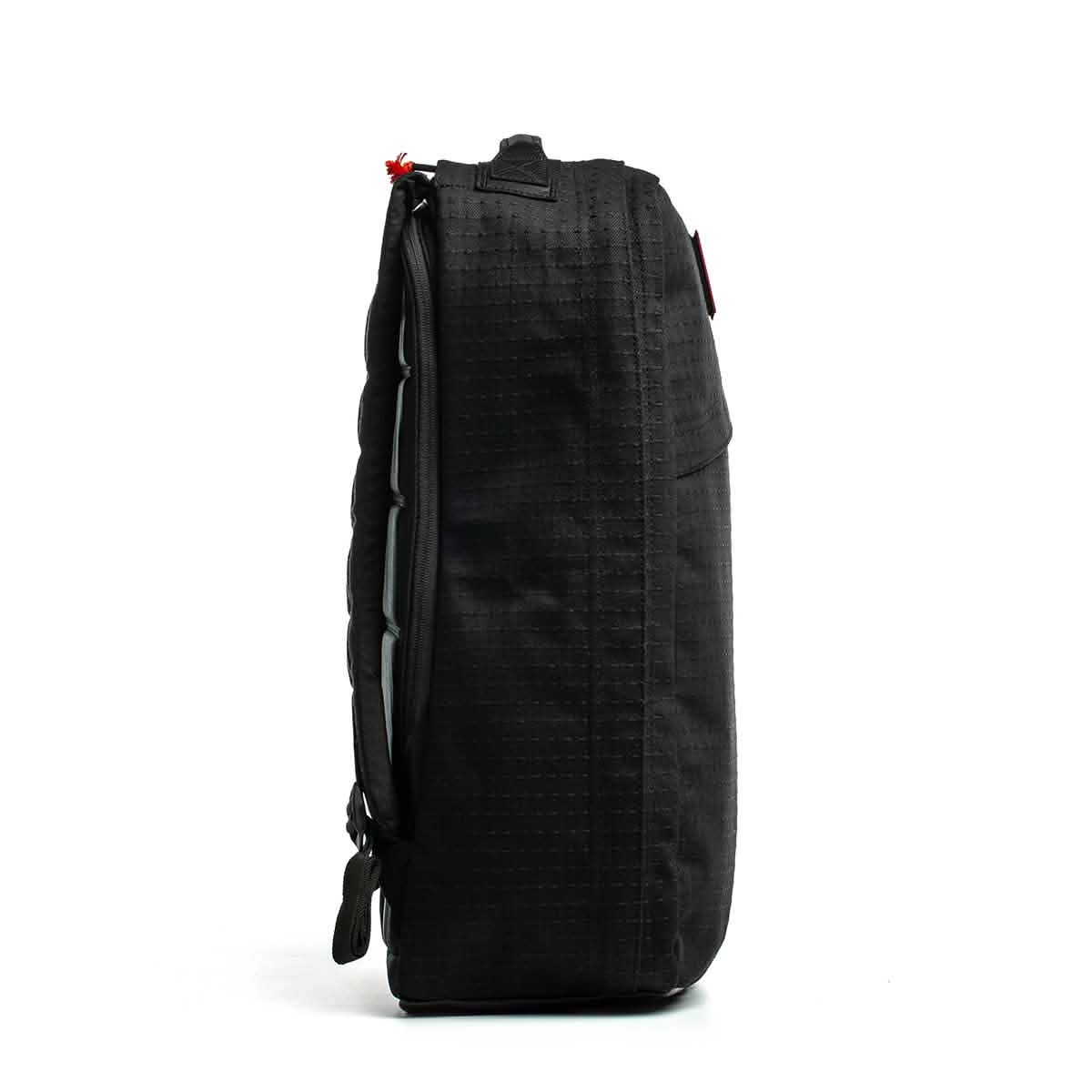 Side view of the black GR1 USA x Carryology - GRXC2 Samurai backpack with a zipper and minimal design, made from premium Japanese cotton, standing upright on a white background.