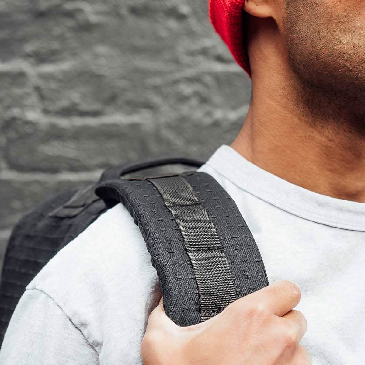 A person in a red beanie and gray shirt holds the strap of the GR1 USA x Carryology - GRXC2 Samurai, made with premium Japanese cotton, over their shoulder.
