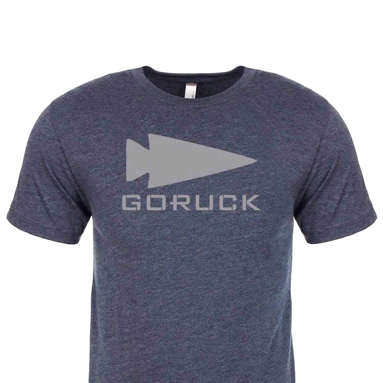 Introducing the "Three Rules Tee - Tri-Blend" : A dark blue t-shirt made from premium tri-blend fabric, adorned with a bold gray triangle and the word GORUCK across the front. Renowned for its superior quality and style, this shirt is crafted with pride in the USA against a pristine white backdrop.