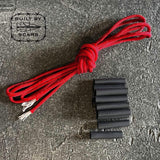 GORUCK red paracord and black heat shrink tubing kit on stone background, Built by Scars logo visible.