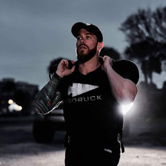 Man wearing GORUCK reflective gear tee and carrying a sandbag during outdoor workout