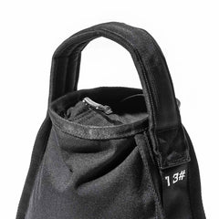 Close-up of a black fabric bag featuring a sturdy handle and zippered top closure, designed in the spirit of endurance. It includes a section with white numbering, reflecting the adaptability of GORUCK's Sand Kettlebells. The background is white.