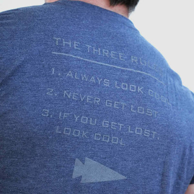 A person wearing a Three Rules Tee - Tri-Blend, semi-famous for its quirky design, displays text on the back listing three rules: 1. Always look cool, 2. Never get lost, 3. If you get lost, look cool—complete with an arrow symbol at the bottom and printed in the USA.