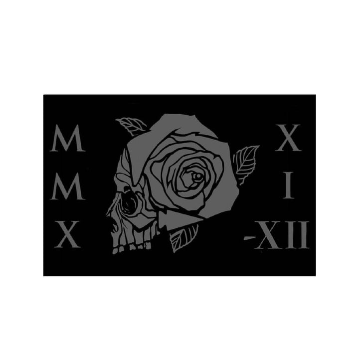 The Patch - GORUCK TRIBE - 2021 from GORUCK showcases a striking black flag with a stylized skull adorned by a blooming rose at its center. Around this central motif, the Roman numerals MMX, XII, and -XII are skillfully arranged. The solid black background accentuates the design, making it ideal for those who engage in challenging ventures like GORUCK Tribe patches.