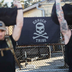GORUCK Tribe flag with skull and crossbones design on a fence, outdoor rucking training scene