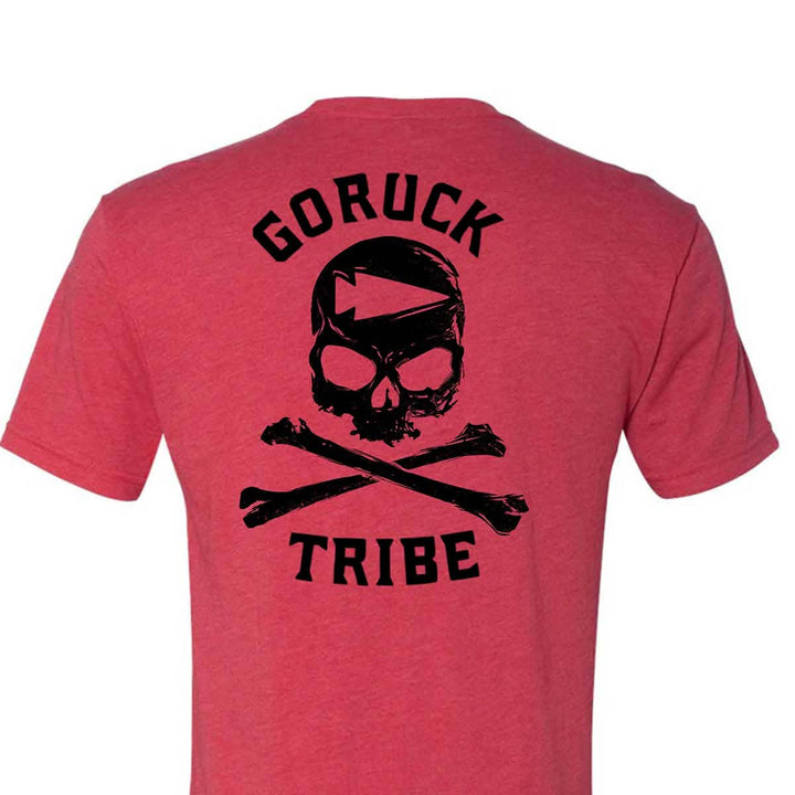 Here is the GORUCK Tribe Tee - Tri-Blend by vendor-unknown, a red T-shirt showcasing the iconic GORUCK Tribe print in black with a skull and crossbones design intertwined with an American flag motif, ideal for those who embrace the shared hardships of every GORUCK Challenge.