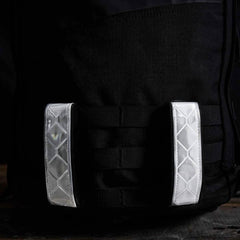 Close-up of black GORUCK rucksack with two reflective white strips on the MOLLE panel