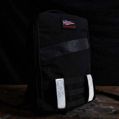 Black GORUCK rucksack with American flag patch and reflective straps on wooden surface